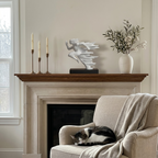 Abstract white running figure sculpture decorating a brick fireplace mantel next to pillar candles and a picture frame
