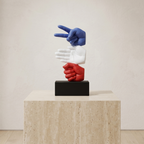 Colorful sculpture of three interlocking hands on a pedestal against a plain background