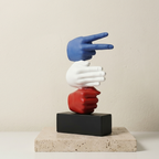 Colorful sculpture of three hands on a black block with a beige background