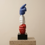Three-dimensional sculpture of interlocking hands in blue, white, and red on a beige background