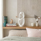 Decorative shelf with books, a rabbit figurine, a white sculpture, and a candle on a bed.