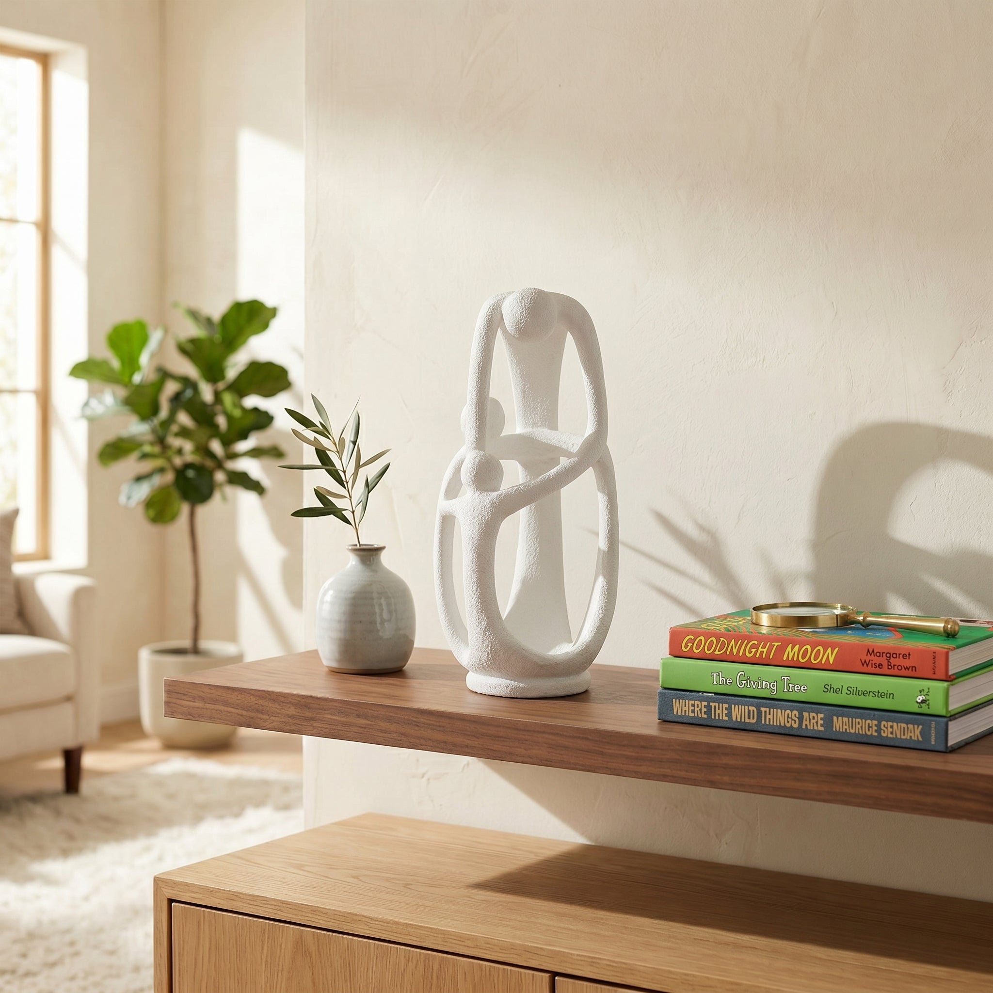 An abstract matte white "INFINITE" family sculpture on a walnut shelf, showing three interlocking stylized figures forming a continuous loop.